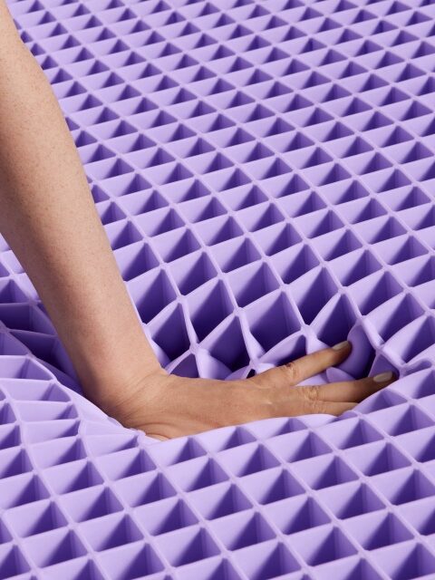 A hand pressing down on a purple textured foam surface creating a distortion.