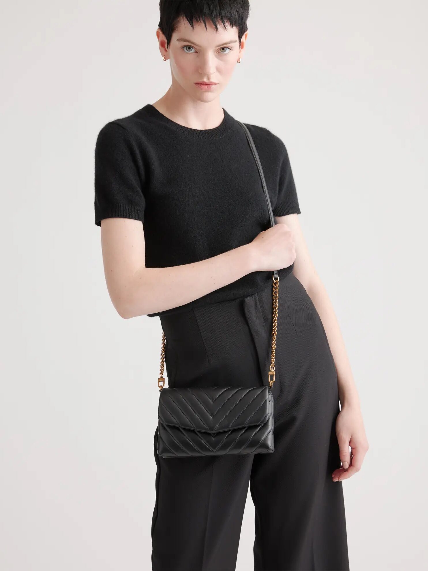 Woman posing with a black chain strap purse.