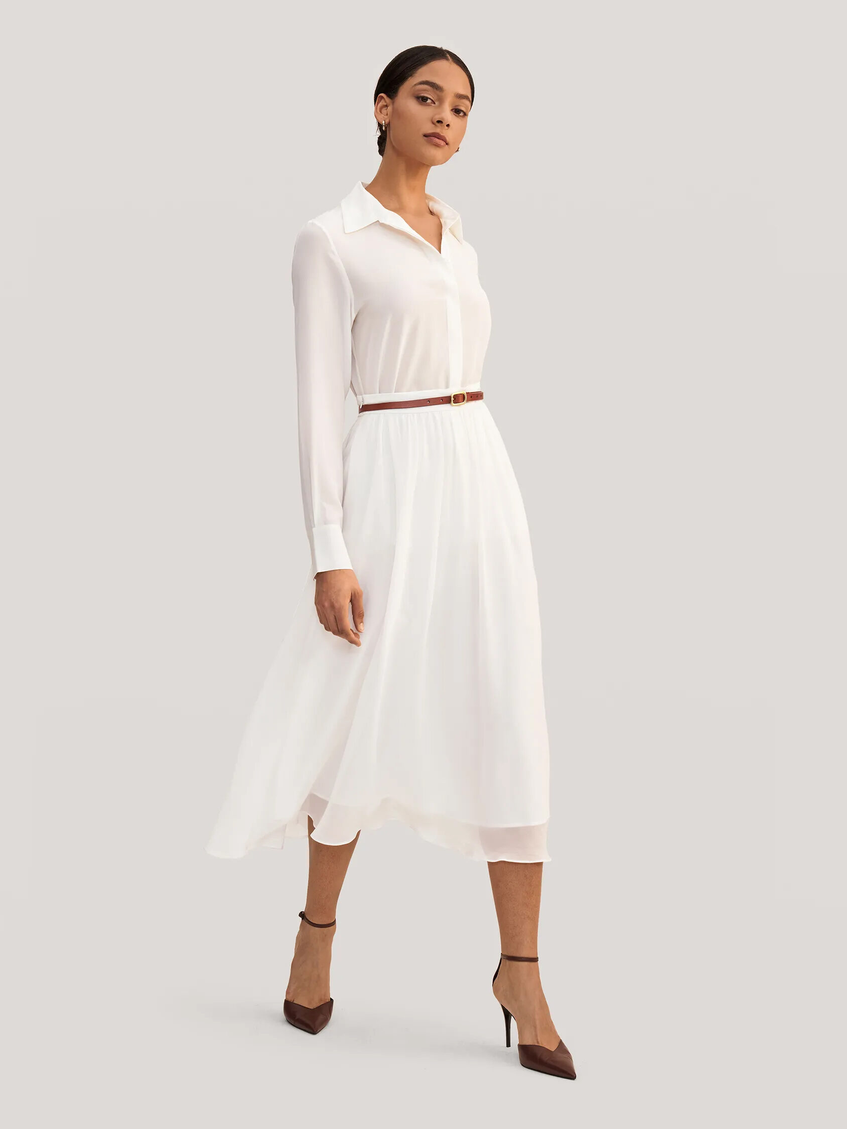 A woman in a white midi dress with a collar and a brown belt, paired with brown high heels.