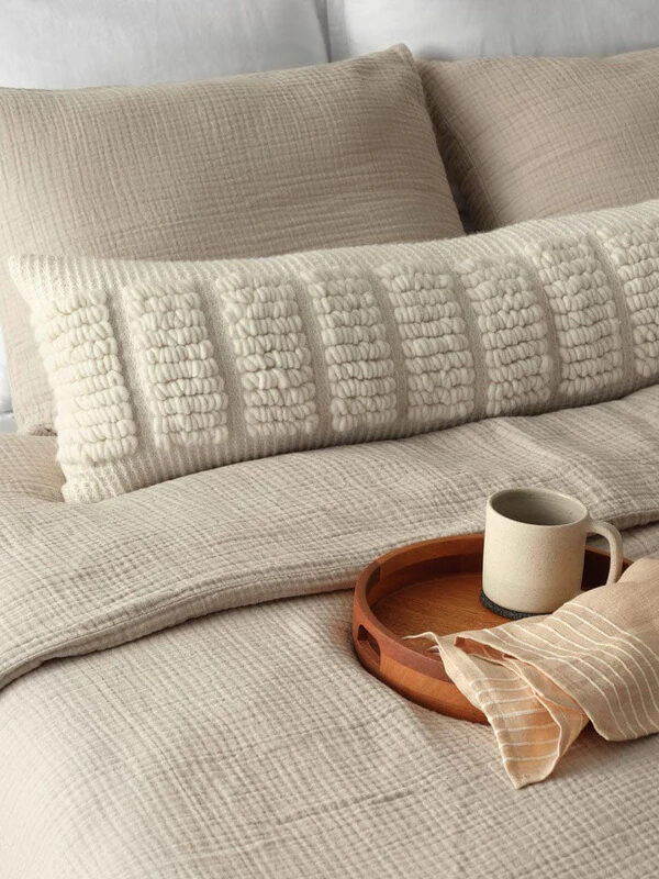 A bed with pillows and a tray with a cup of coffee.