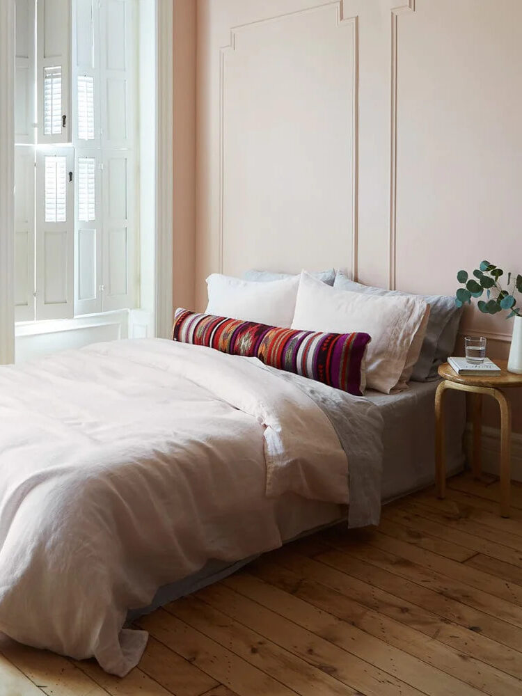 A pink bedroom with wooden floors and a bed.