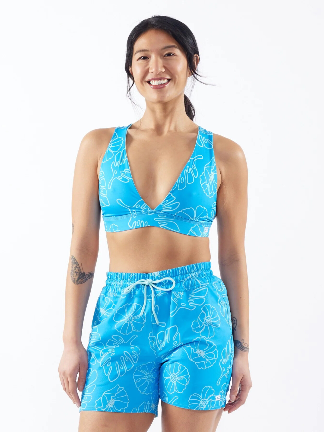 Woman in blue floral swimwear smiling against a white background.