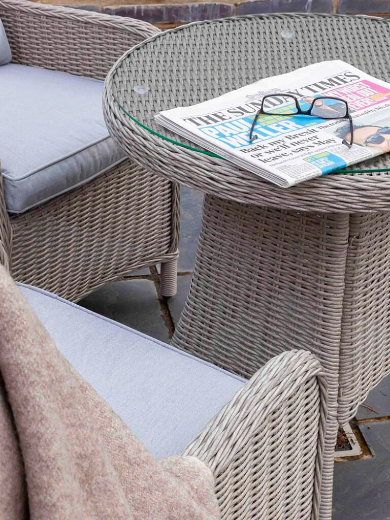 A wicker table and chairs with a newspaper on it.