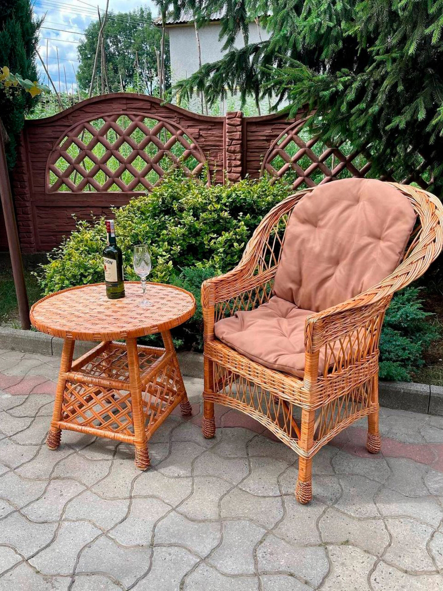 A wicker chair and table with a bottle of wine.
