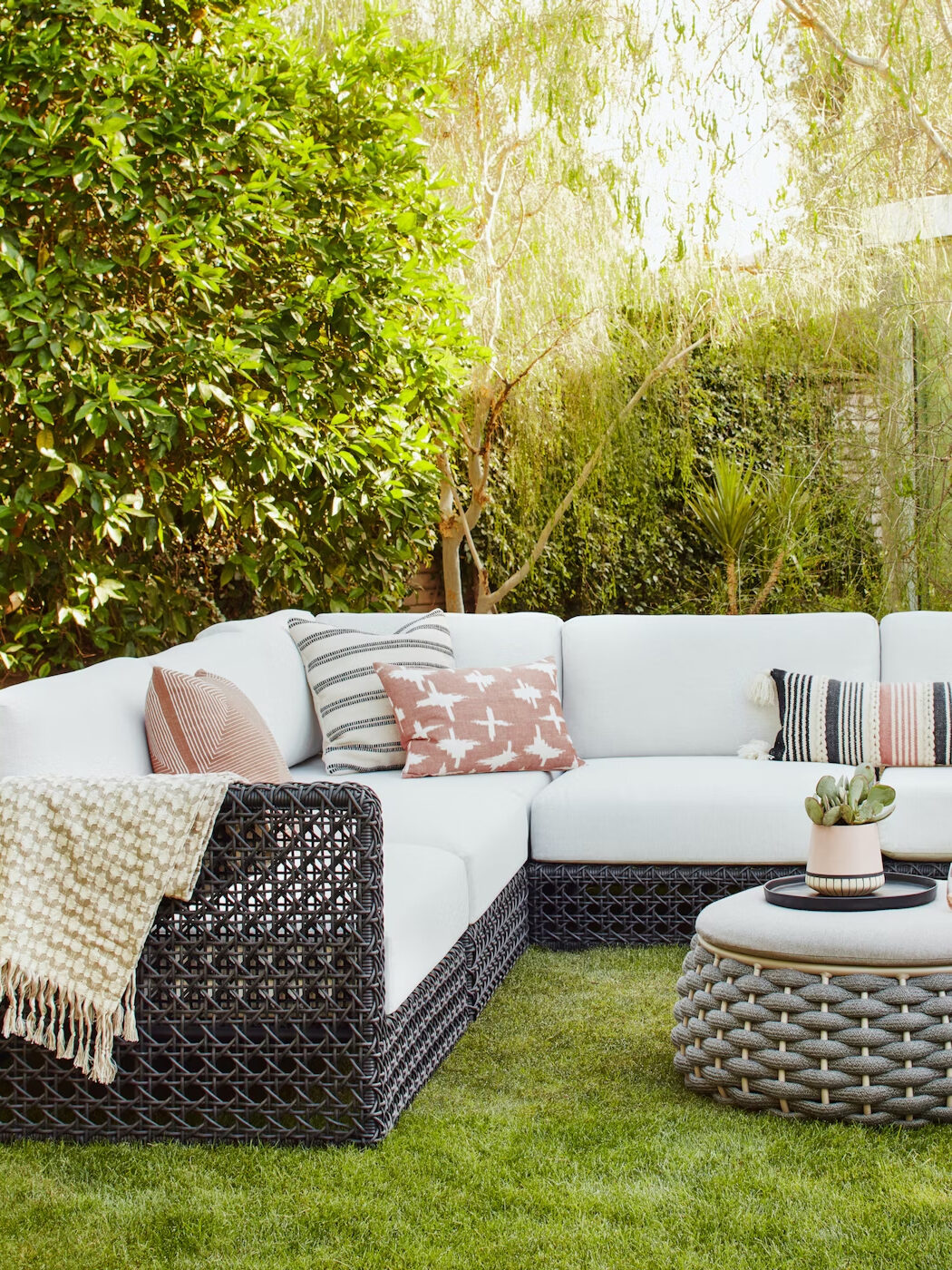 A black and white outdoor sectional with pillows and a coffee table.