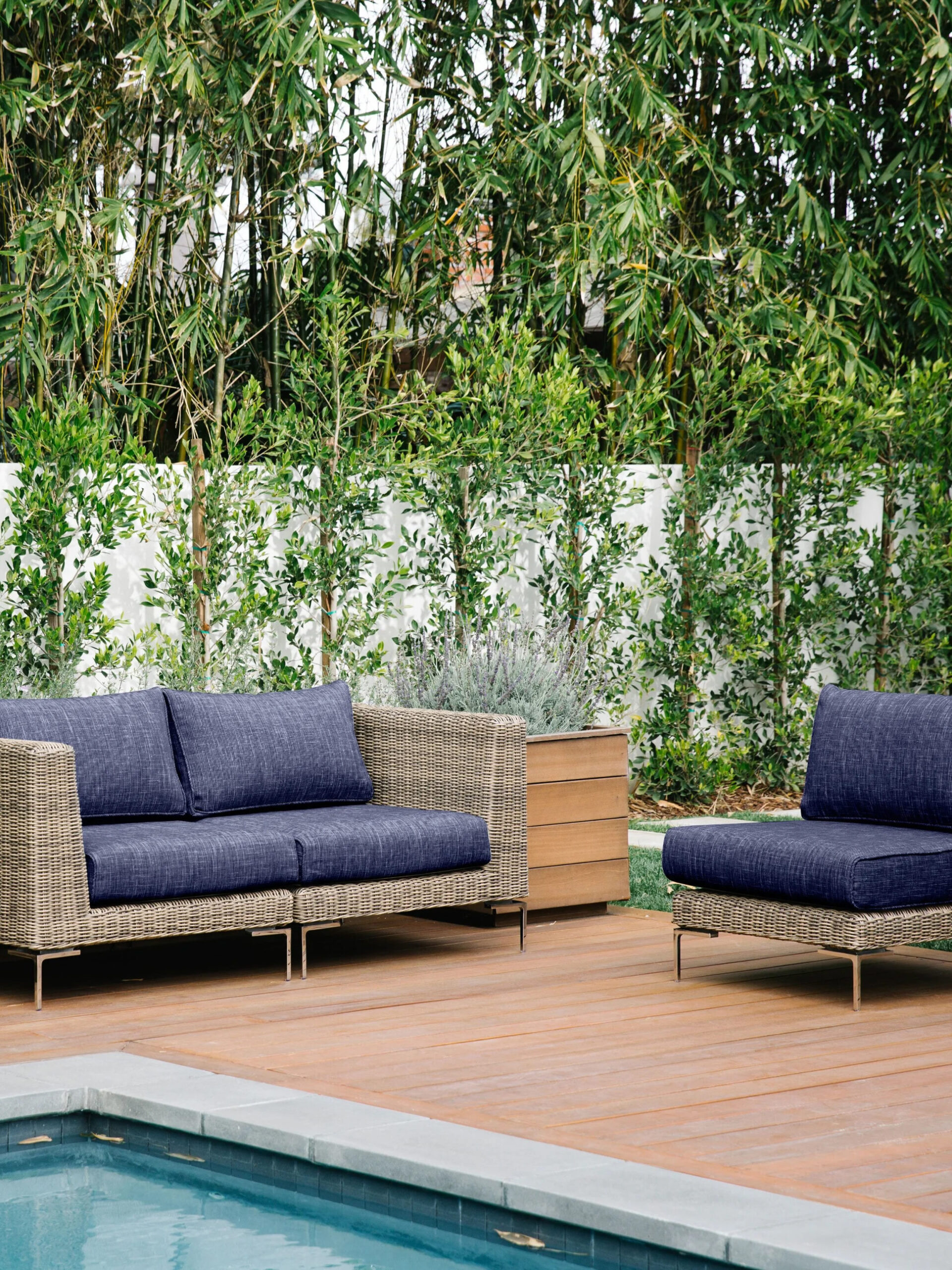 A wooden deck with a pool and a wicker furniture set.