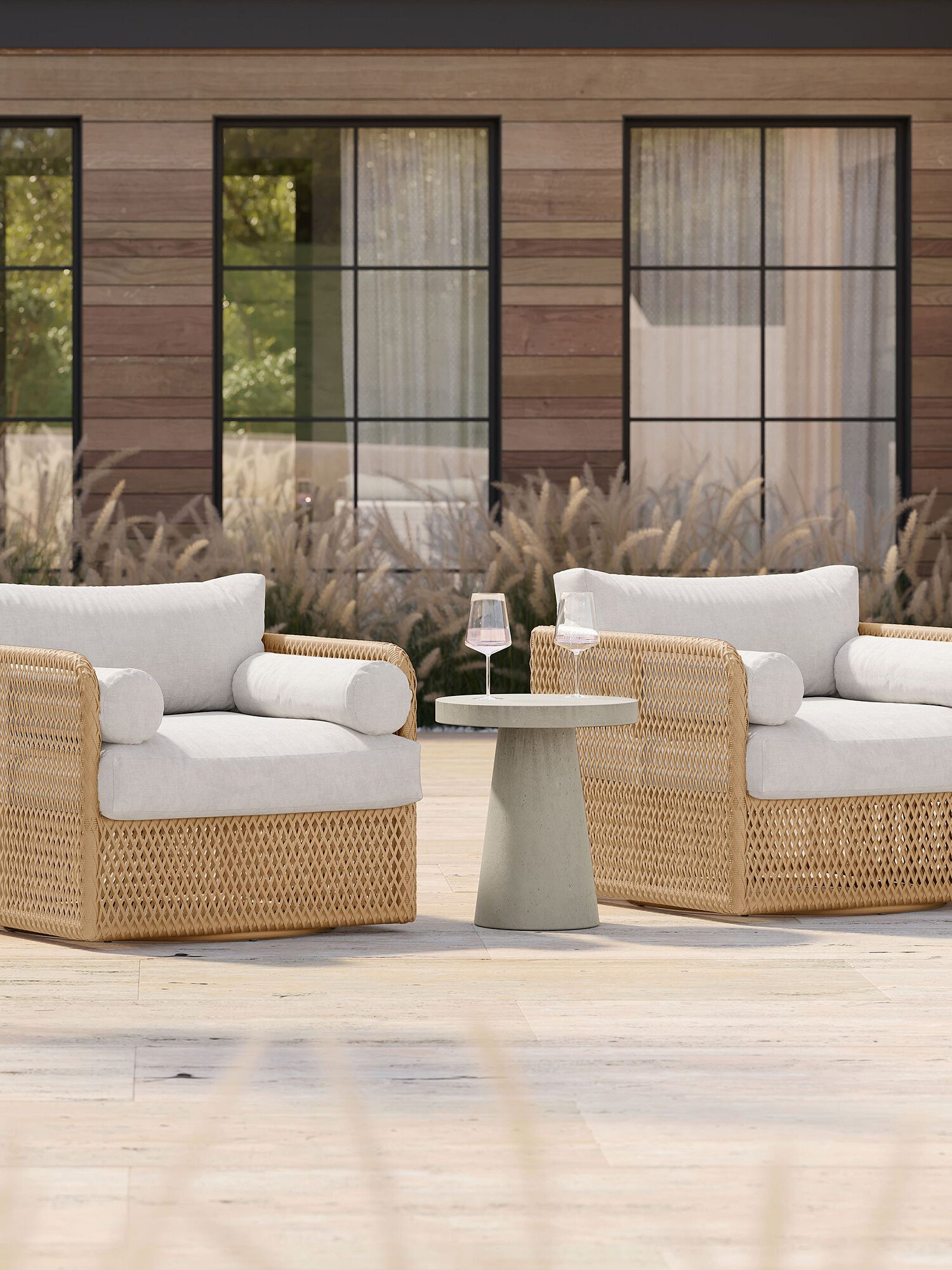 Two wicker lounge chairs on a patio with a glass of wine.