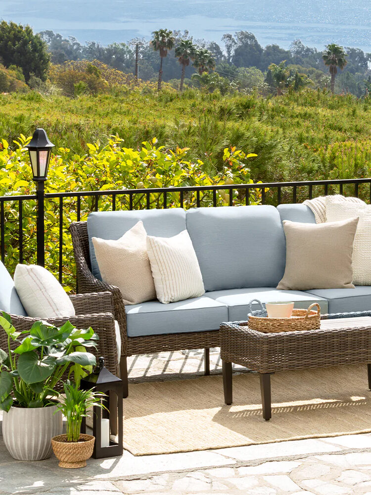 A wicker patio furniture set on a deck.
