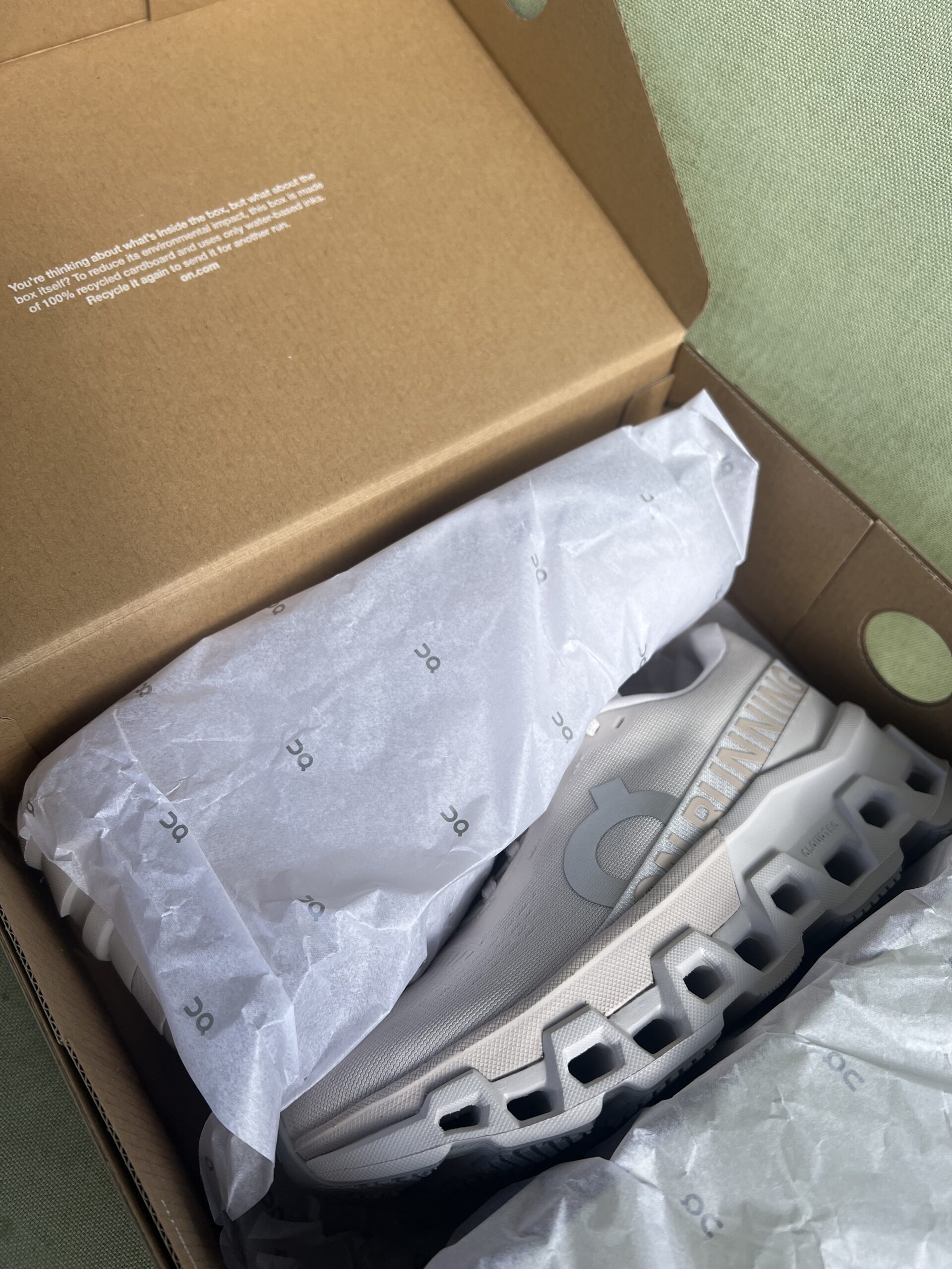 A new pair of shoes in a cardboard box, partially covered with on-branded tissue paper.