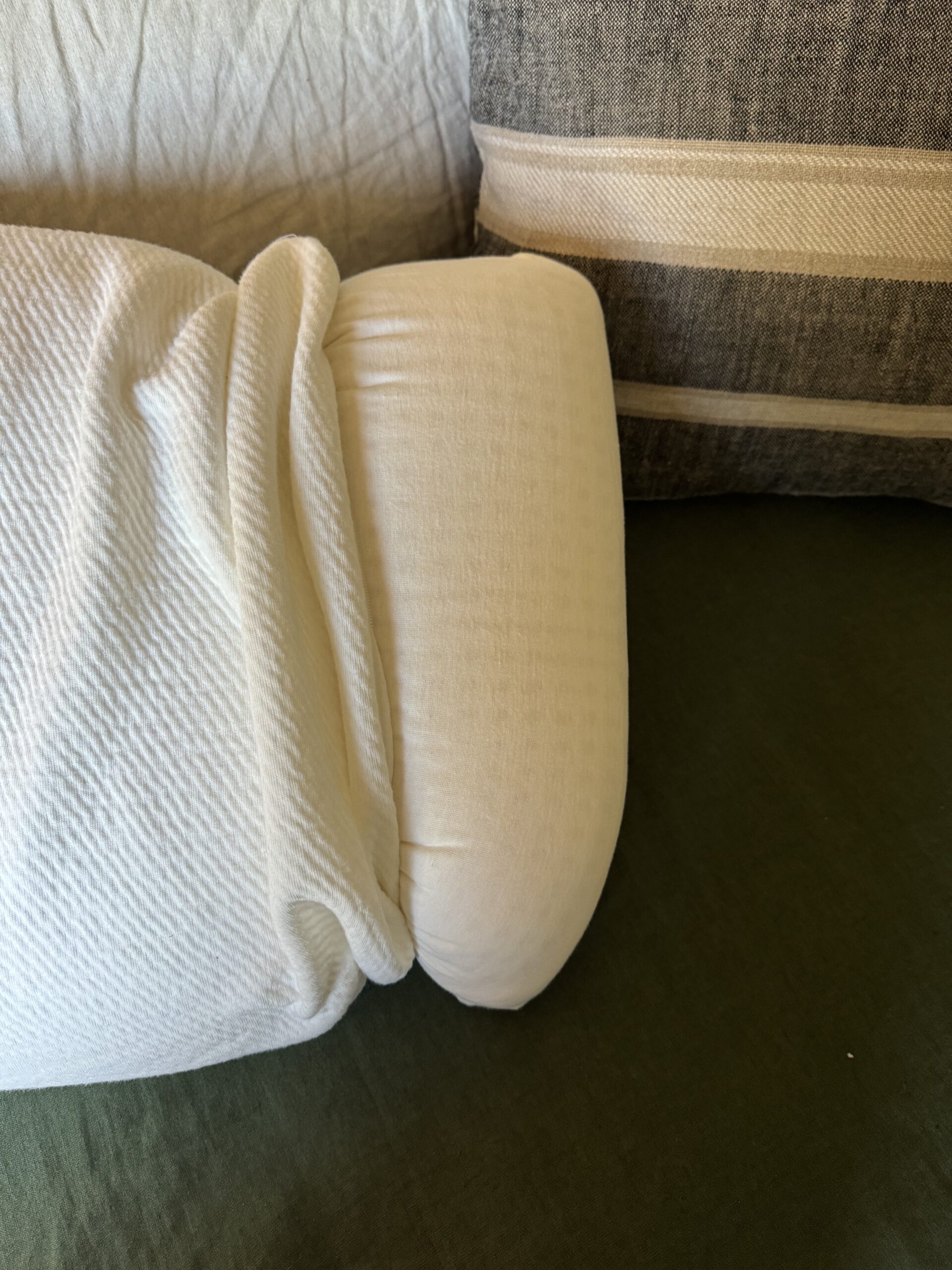 A white crumpled blanket on a couch with green upholstery.