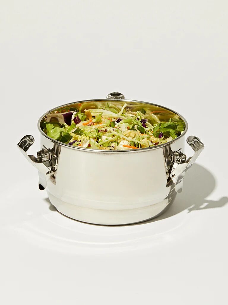 A white pot filled with a colorful mixed salad, featuring greens and shredded vegetables, isolated on a white background.