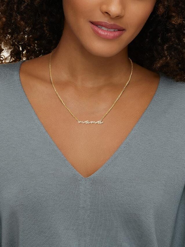 Close-up of a woman wearing a "mama" necklace with a v-neck top.