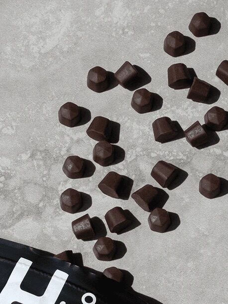Scattered dark chocolate pieces on a gray textured surface.