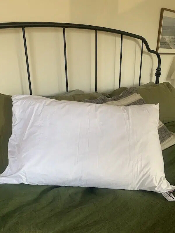 A pillow in a white case on a neatly made bed.