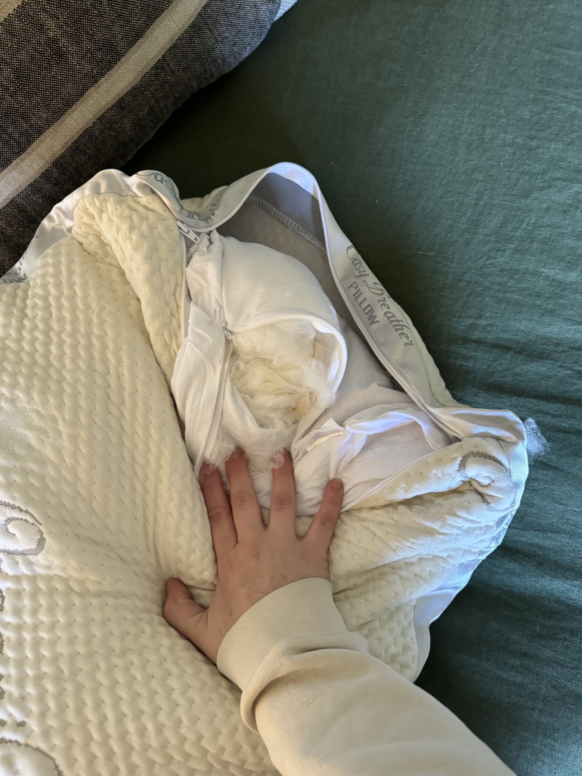 A person's hand pressing down on a white, plush blanket with a fabric tag visible.
