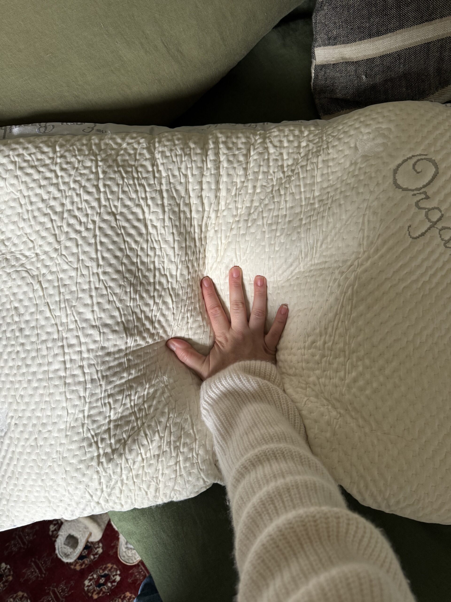 A hand pressing down on a textured white pillow.