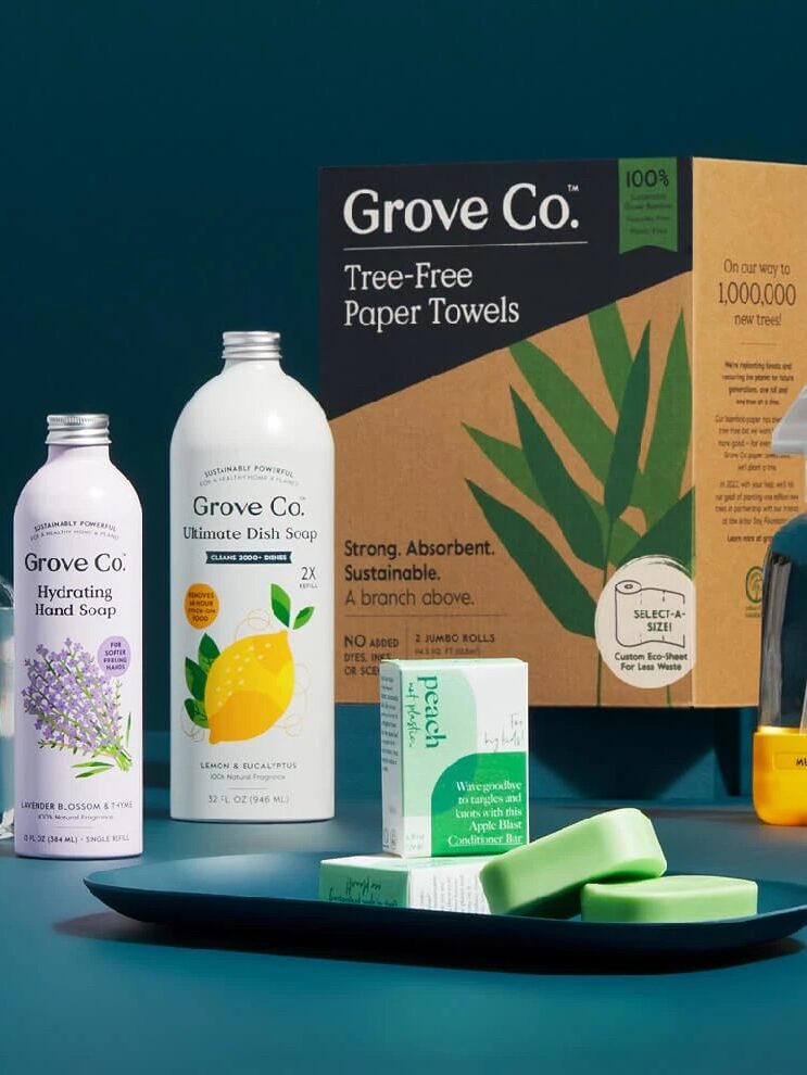 Eco-friendly cleaning products displayed on a teal background, featuring biodegradable soaps, sprays, and tree-free paper towels.