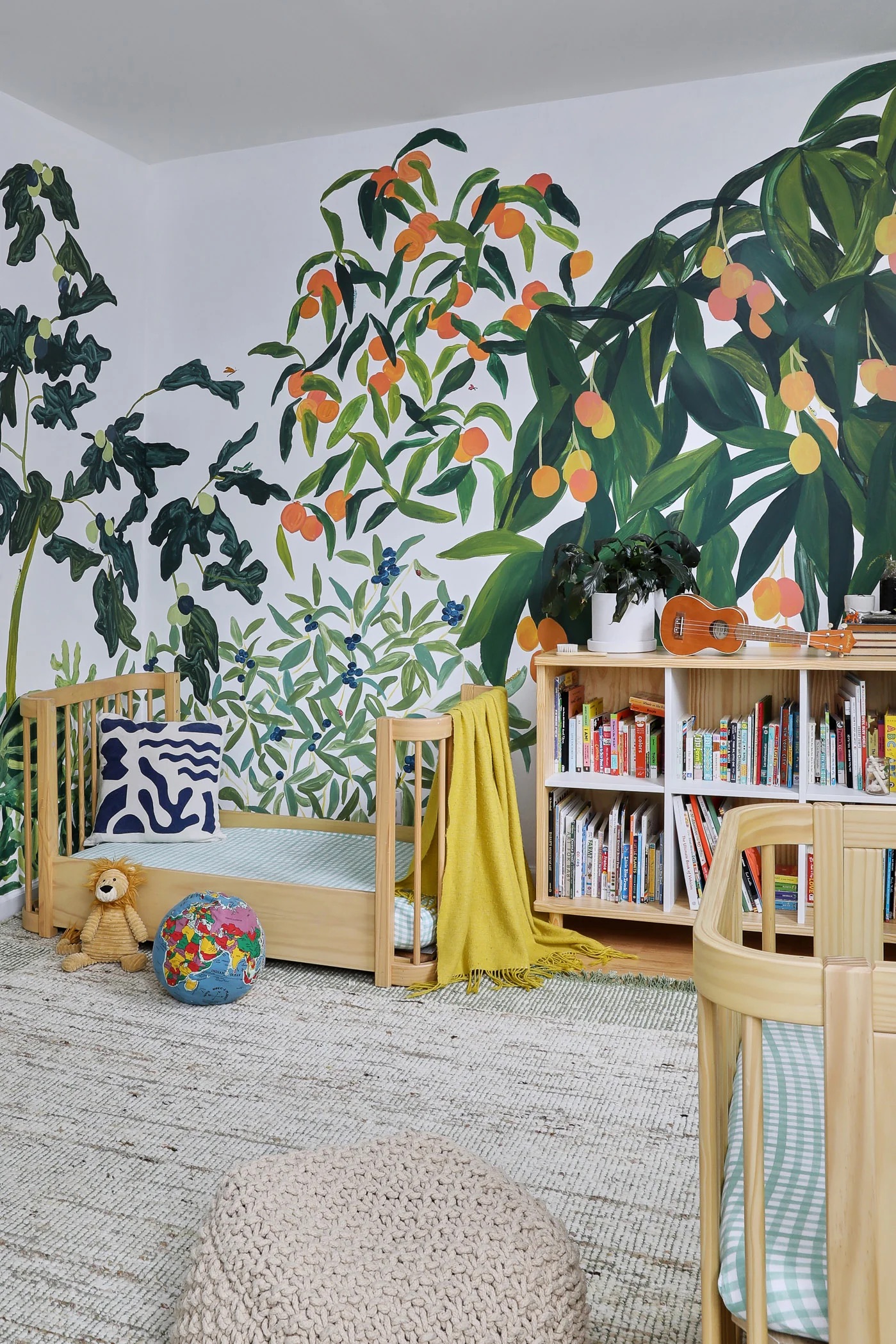 A colorful and vibrant children's bedroom with a botanical wallpaper, wooden furniture, and plush toys.