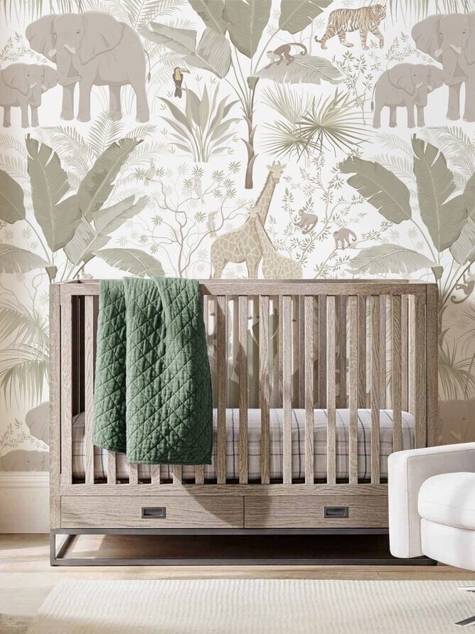 A stylish nursery room with a crib, armchair, and dresser against a jungle-themed wallpaper.