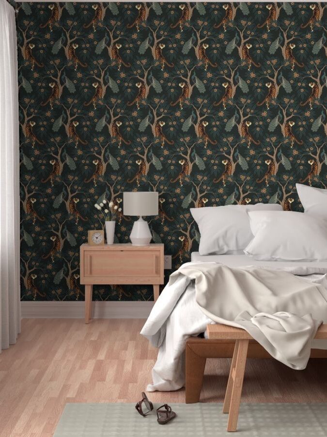 A modern bedroom with dark floral wallpaper, white bedding, a wooden side table with a lamp, and a pair of glasses on the floor.