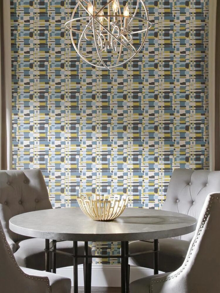 Round dining table with four chairs in a room with a colorful mosaic wall and a modern chandelier.