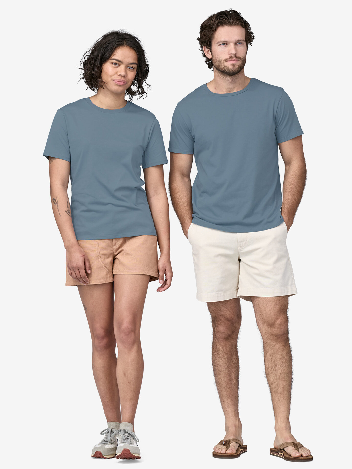 A man and a woman standing side by side, wearing plain blue t-shirts and shorts, looking directly at the camera with neutral expressions.