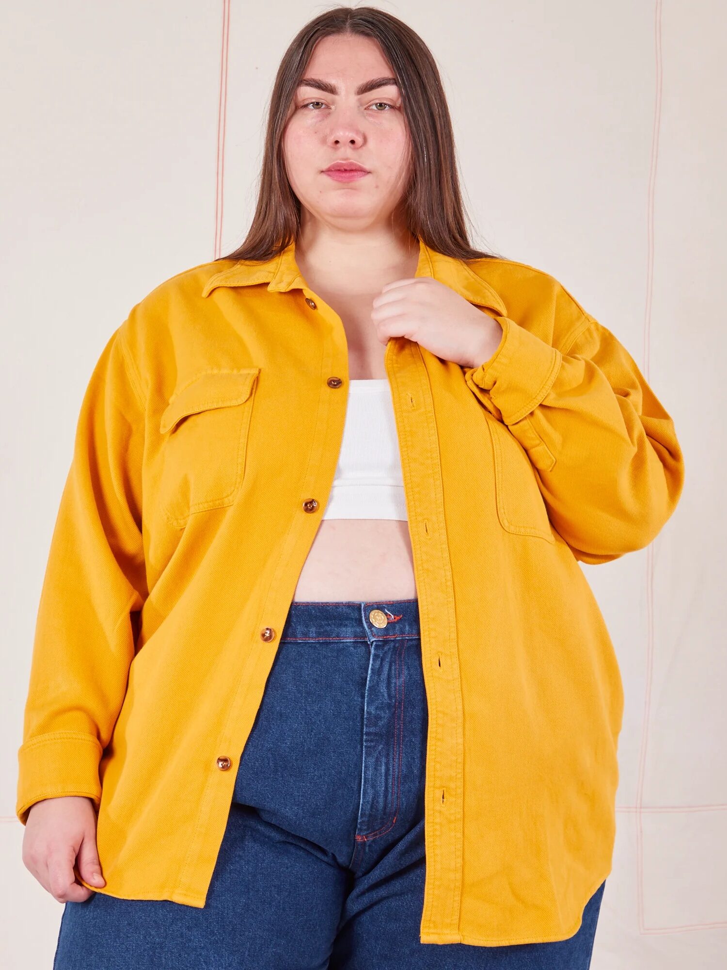 A woman in a yellow shirt and blue jeans posing for a photograph.