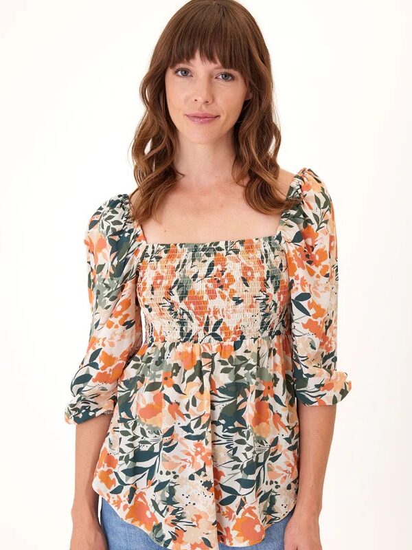 Woman in a floral blouse posing against a white background.