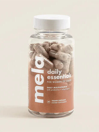 A bottle of mela daily essentials multivitamins for women, labeled vegan and non-gmo, against a plain beige background.