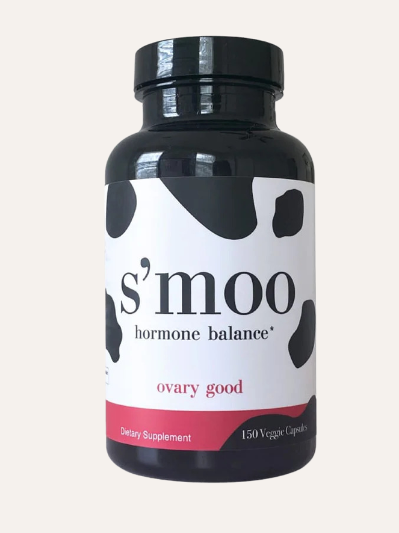A bottle of s'moo hormone balance dietary supplements with a cow print design, labeled "ovary good," containing 150 veggie capsules.