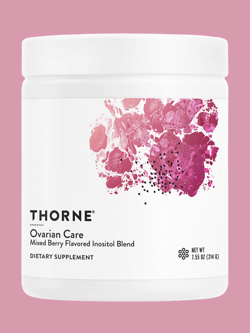 A white container of thorne ovarian care dietary supplement with a mixed berry flavor, illustrated with a berry design, against a plain pink background.