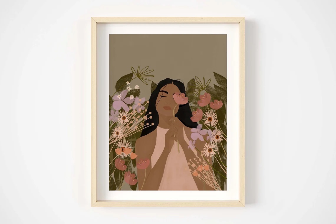Illustration of a woman surrounded by flowers, framed and hung on a white wall.