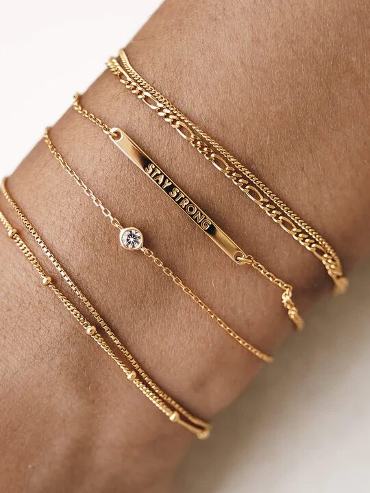 A variety of thin gold bracelets from Linjer on a model's wrist. 