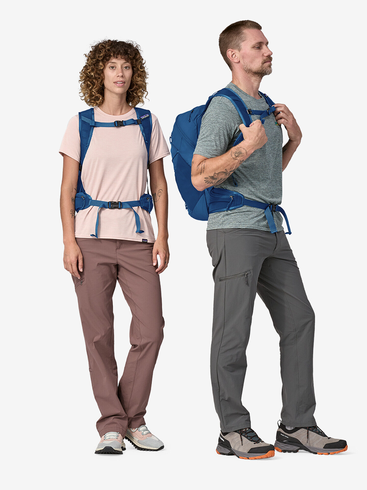 Two hikers wearing technical clothing and backpacks standing back-to-back, looking towards opposite directions.