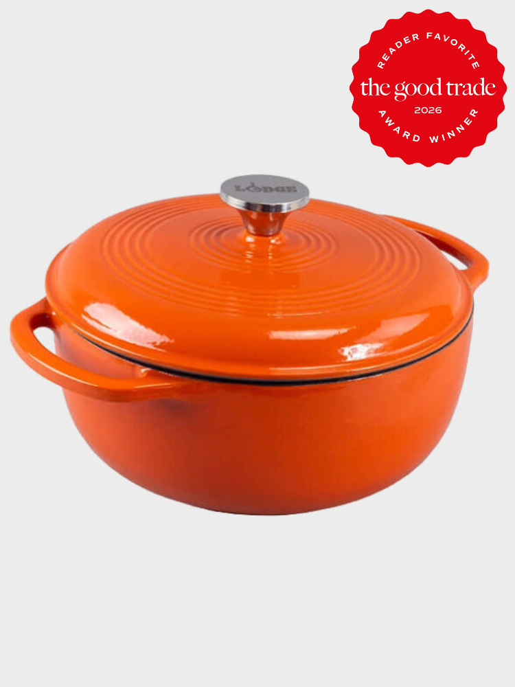 An orange cast iron Dutch oven with lid and side handles, featuring a "Lodge" logo on the knob. A red badge indicates it is a 2026 award winner from The Good Trade.