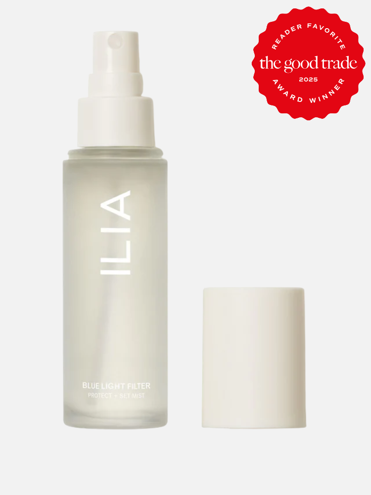 A frosted spray bottle labeled "ILIA Blue Light Filter Protect + Set Mist" with a white cap removed, alongside a red "The Good Trade 2023 Award Winner" badge.