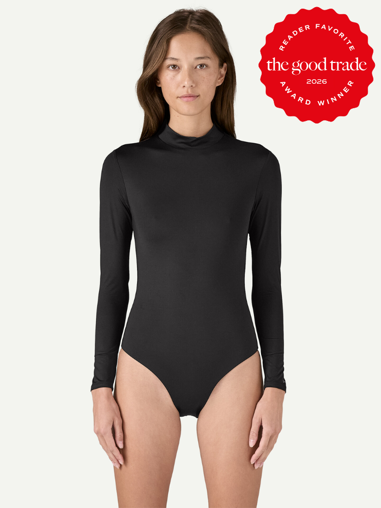 A woman wears a long-sleeve black bodysuit and stands against a plain background. A red badge in the top right corner indicates "The Good Trade Award Winner 2026.