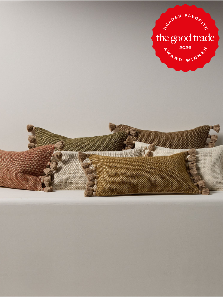 Four rectangular throw pillows in earthy tones with tassels are arranged on a white surface; a red "The Good Trade 2026 Award Winner" badge is in the top right corner.