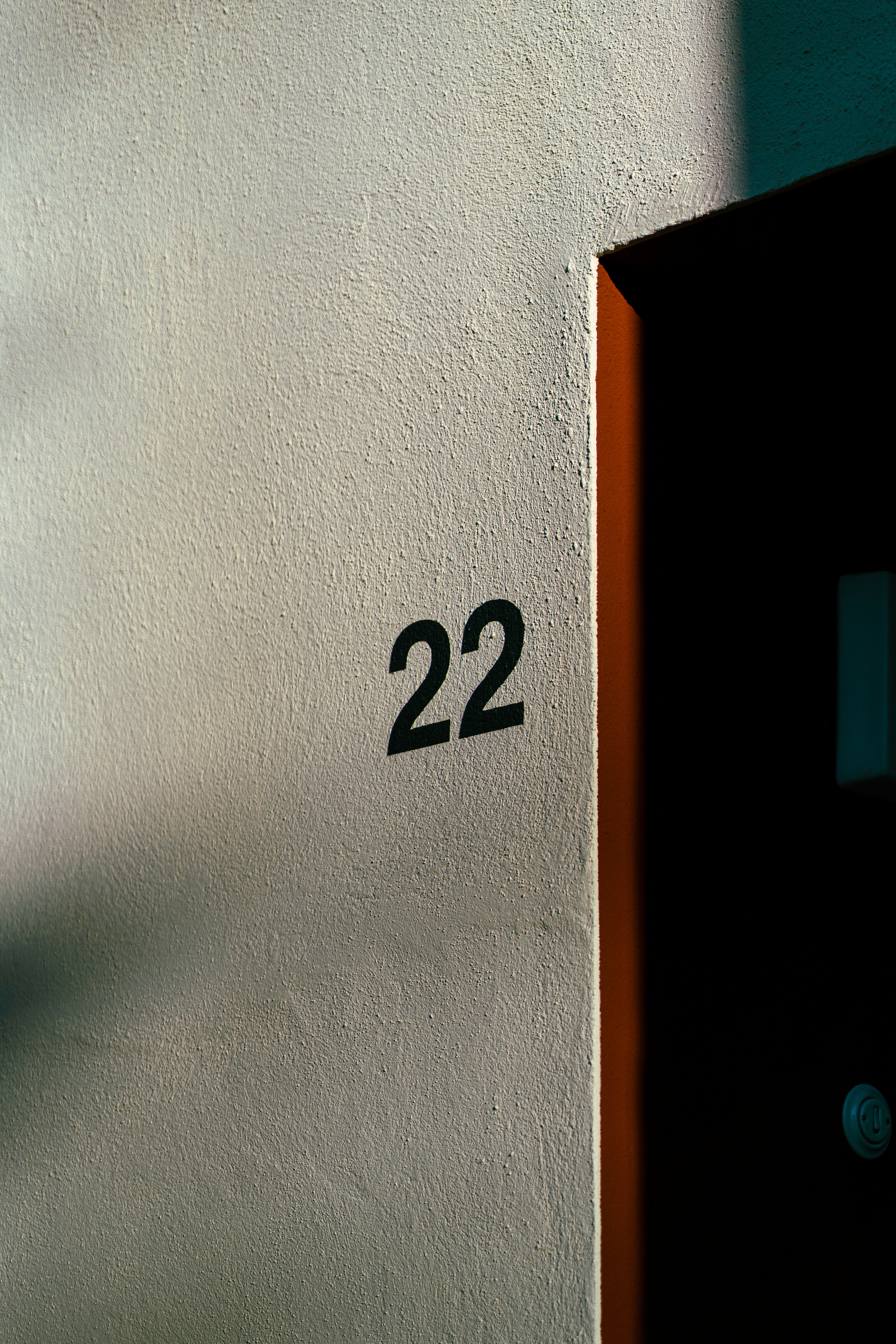 The angel number 22 on a white wall next to a dark door frame.