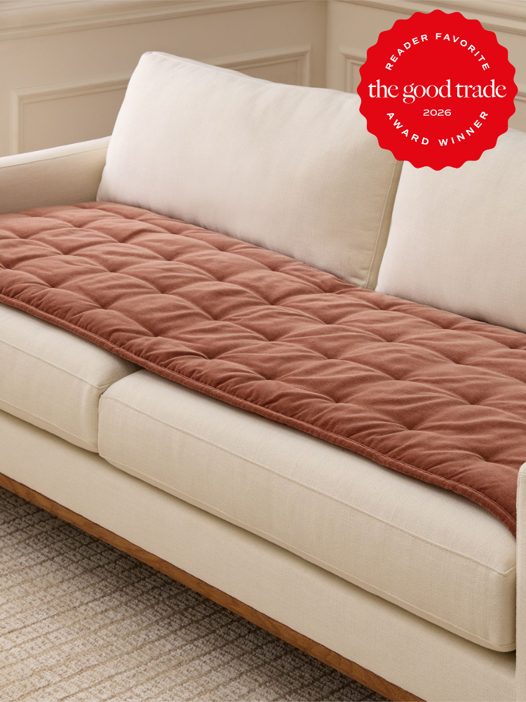 A cream-colored sofa with a quilted rust-colored cushion on the seat. A red badge in the top right corner reads, "The Good Trade Award Winner 2026 Reader Favorite.
