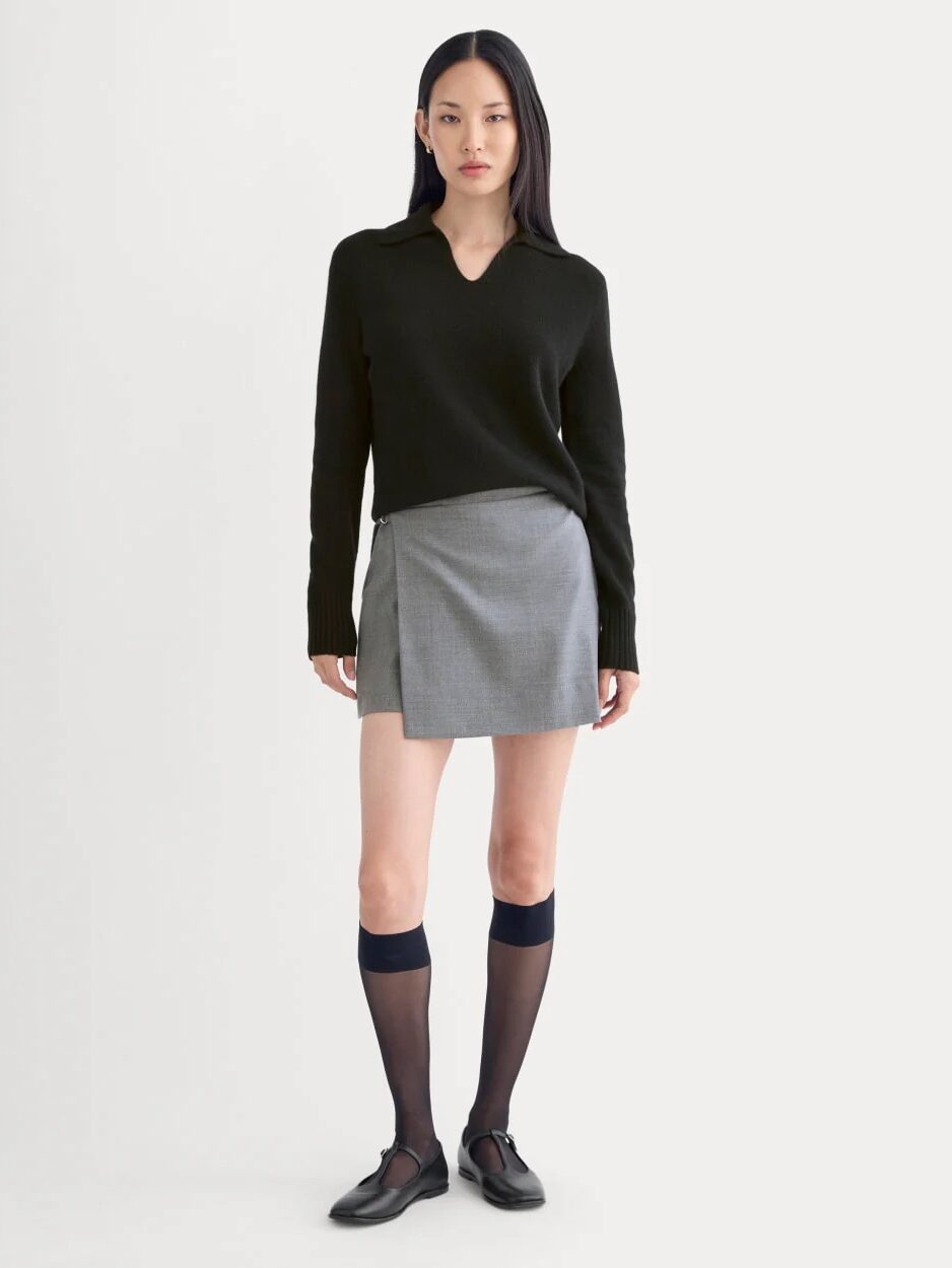 A woman in a skirt and black sweater.