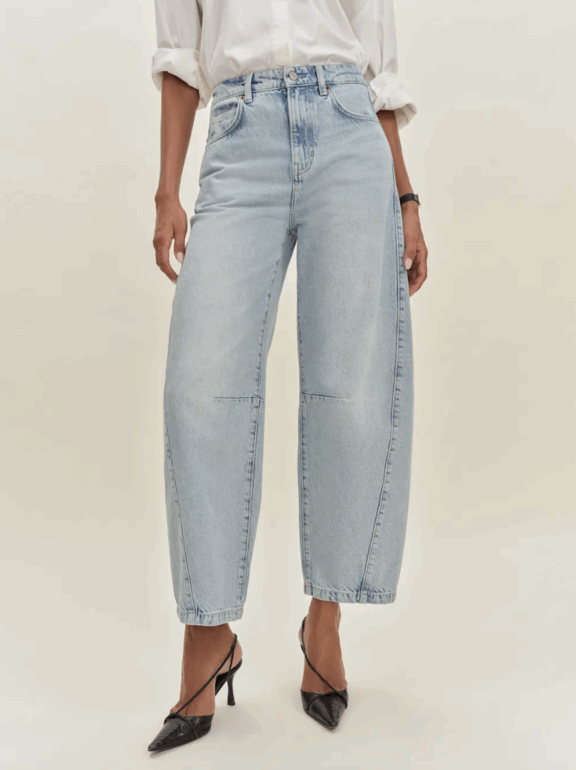 A person wearing light blue wide-leg jeans, a white long-sleeve shirt with rolled-up sleeves, and black pointed-toe heels.