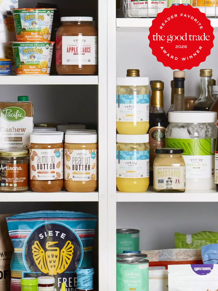 A pantry shelf stocked with various jars, cans, and packaged food items, including nut butters, sauces, and snack chips, organized neatly.