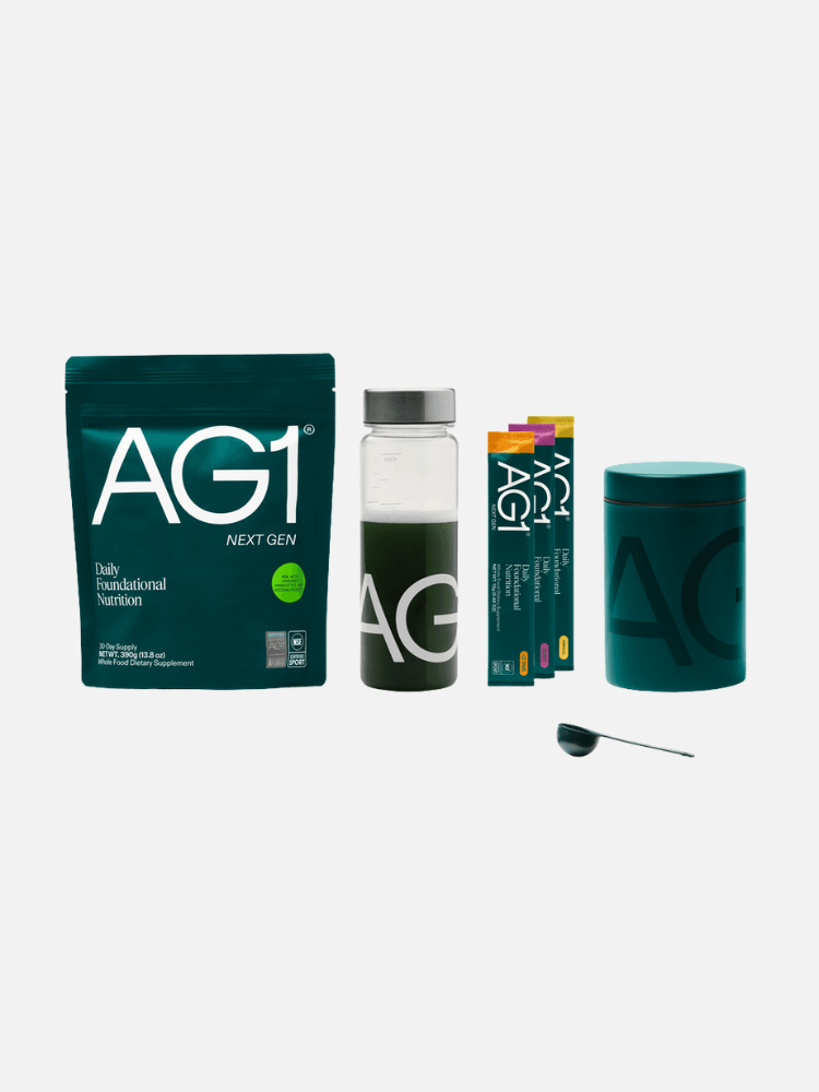 A lineup of AG1 nutrition products, including a pouch, a shaker bottle with green drink, single-serve packets, a canister, and a scoop, all with branded packaging on a white background.