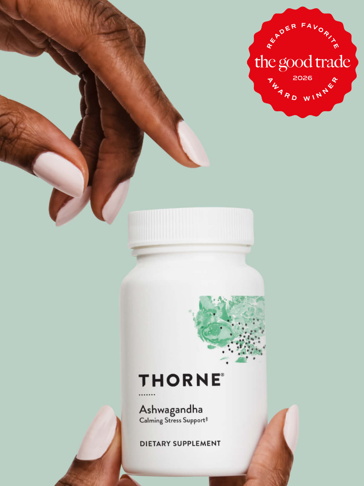 A person holds a white bottle of Thorne Ashwagandha dietary supplement against a light green background. A red badge in the corner reads “The Good Trade Award Winner 2026.