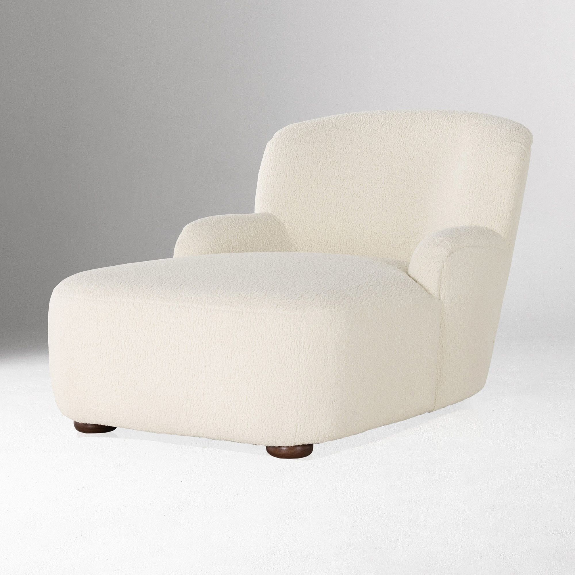A modern, armless lounge chair upholstered in off-white textured fabric with round wooden feet on a plain white background.