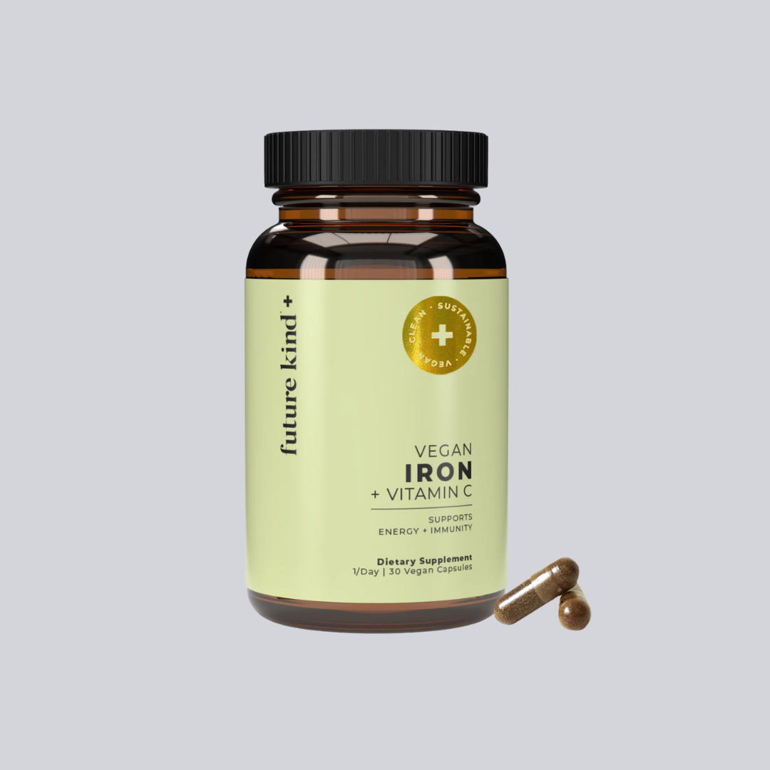 A bottle of Future Kind Vegan Iron + Vitamin C dietary supplement with two vegan capsules displayed beside it.
