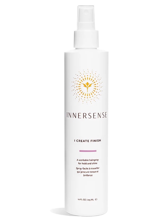 A white spray bottle of Innersense I Create Finish hairspray, featuring a gold sunburst logo and text describing it as a workable hairspray for hold and shine.