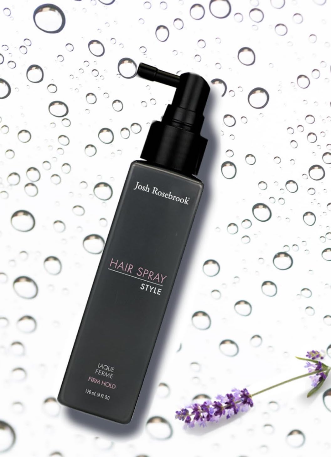 A black bottle of Josh Rosebrook Hair Spray rests on a background with water droplets and a sprig of lavender.