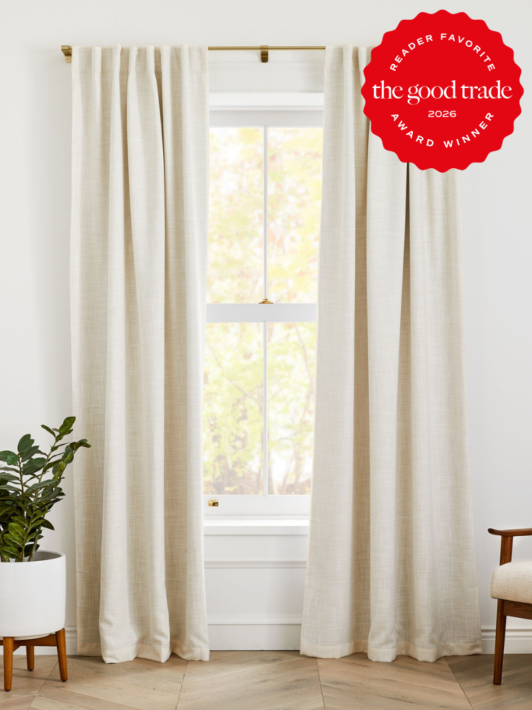 White curtains hang on a brass rod in front of a window with light filtering through. A potted plant sits on the left. A red award badge is displayed in the upper right corner.